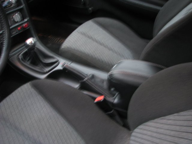 Interior of a car showing gear shifter, handbrake, and armrest.