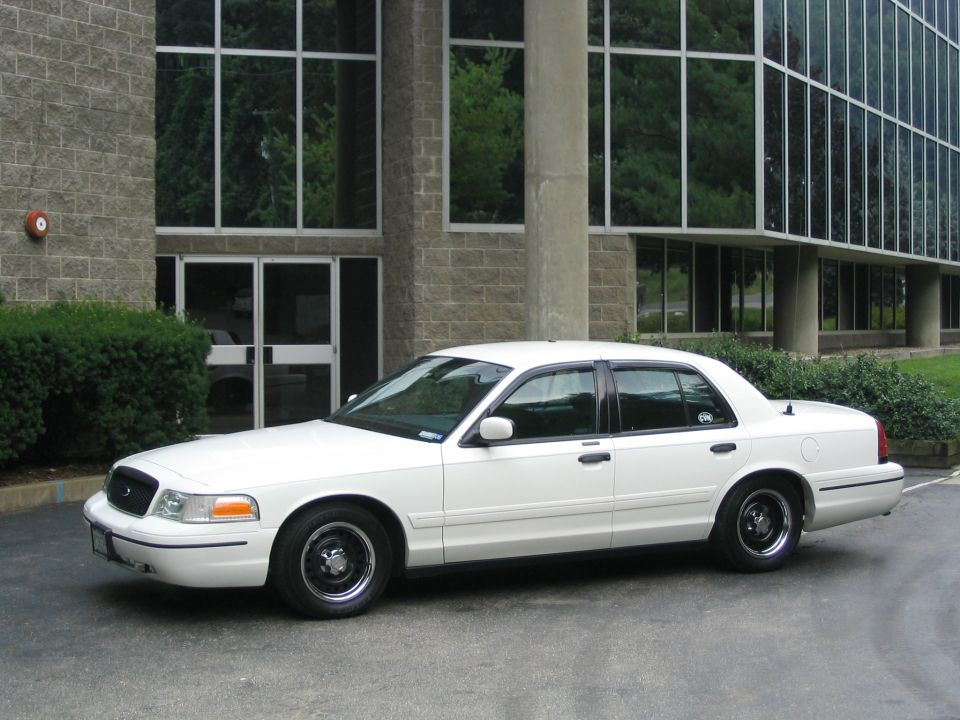 White 1998 Ford Crown Victoria sedan parked outside a modern building