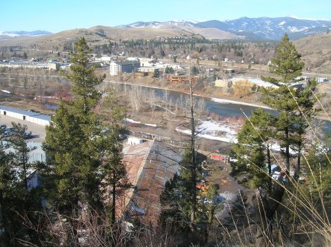 1996 Ford Bronco - A panoramic view of a town nestled in a valley with a river running through it. Mountains are visible in the background under a clear blue…