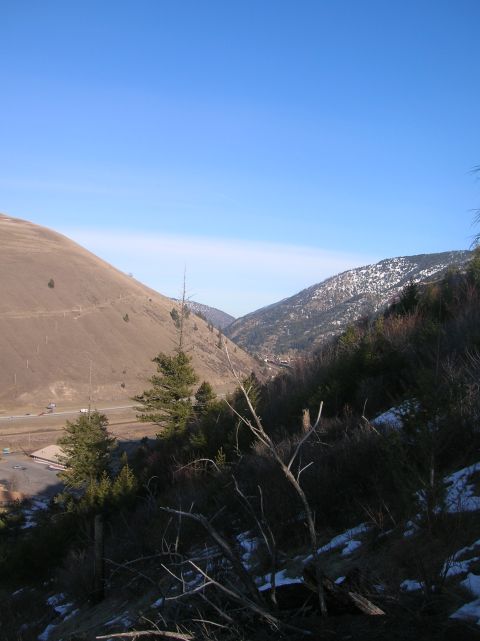 1996 Ford Bronco - A wide shot of a valley with a clear blue sky above. A brown, grassy hillside is on the left, and a darker, tree-covered mountain with patc…
