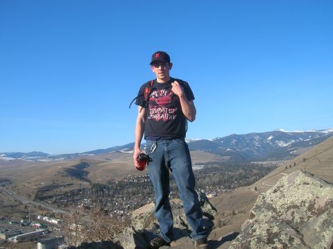 1996 Ford Bronco - A young man stands on a rocky outcrop overlooking a valley with a town and mountains in the background.