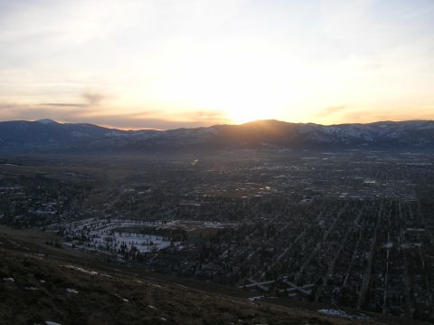 1996 Ford Bronco - A wide aerial view of a city nestled in a valley at sunset, with mountains in the background.