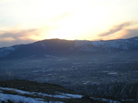 1996 Ford Bronco - A panoramic view of a valley and mountains at sunset. The sky is bright with clouds, and the mountains are covered in snow.