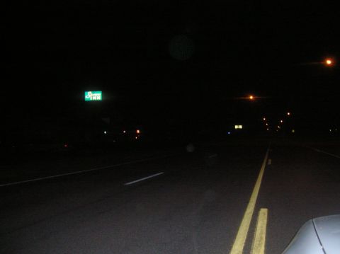 1996 Ford Bronco - A nighttime view of a road with a lit "Sleep Inn" sign visible on the left. The headlights of the vehicle illuminate the asphalt and yellow…