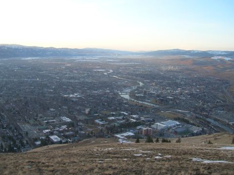 1996 Ford Bronco - A panoramic view of a city nestled in a valley, with mountains in the distance and a river flowing through it. The foreground shows a grass…