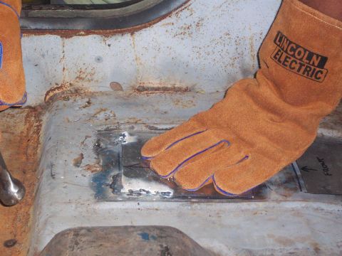 1978 Jeep CJ5 - Welding a patch onto a rusty interior floor pan, with an arrow indicating the front of the vehicle.
