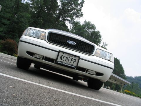 1998 Ford Crown Victoria - White Ford Crown Victoria parked outdoors, showing its front grille and headlights from a low angle.