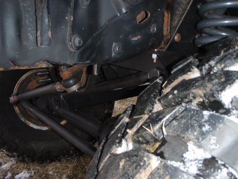 1996 Ford Bronco - A close-up view of the front suspension and steering components of a 1996 Ford Bronco, with a large, muddy off-road tire in the foreground.