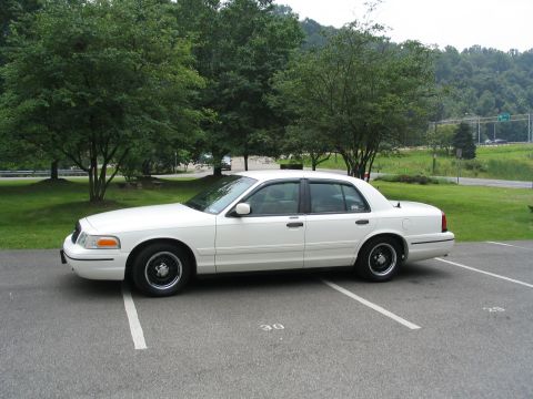 1998 Ford Crown Victoria - A white 1998 Ford Crown Victoria is parked in a lot, showing its side profile.