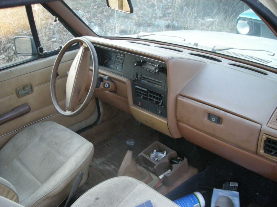 Worn tan interior of an older vehicle showing dashboard and steering wheel