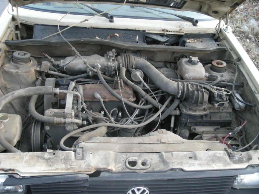 Dusty inline-four engine bay of a white Volkswagen with hood raised