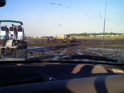 1996 Ford F-150 - A large, white, multi-passenger vehicle with large tires is parked in a muddy field. In the background, several other vehicles and tents ar…