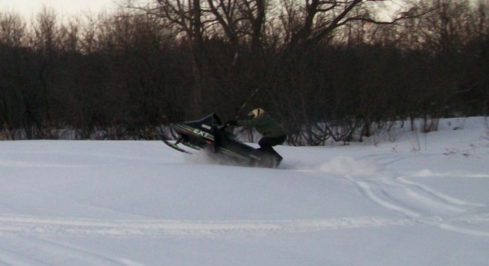 Person riding a snowmobile in a snowy field.