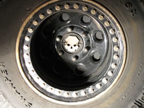 2004 Jeep Wrangler - A close-up view of a black aftermarket wheel with a skull-shaped center cap on a Jeep Wrangler. The wheel is mounted on a tire with visible…