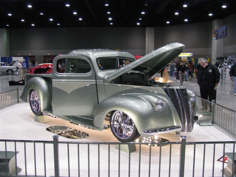 Customized silver and gray pickup truck with hood open at a car show