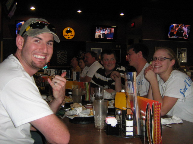 Group of people smiling at a table in a dimly lit sports bar