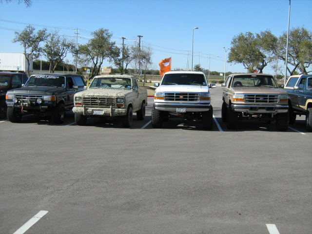 Row of lifted Ford Broncos and trucks parked in a lot