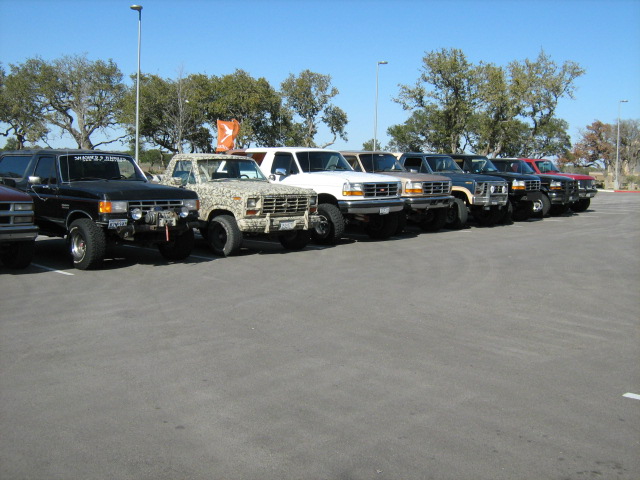 Long row of lifted Ford trucks and Broncos parked in a lot