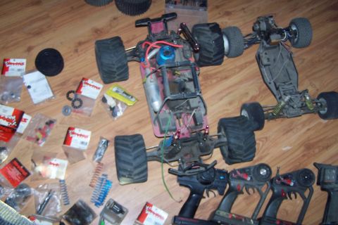 2004 Arctic Cat F-7 Firecat - Collection of RC car parts and two chassis laid out on a wood floor, with multiple controllers visible.