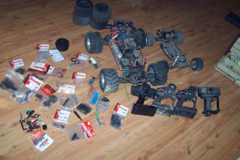 2004 Arctic Cat F-7 Firecat - A collection of RC cars, controllers, and spare parts are spread across a wood-grain surface.