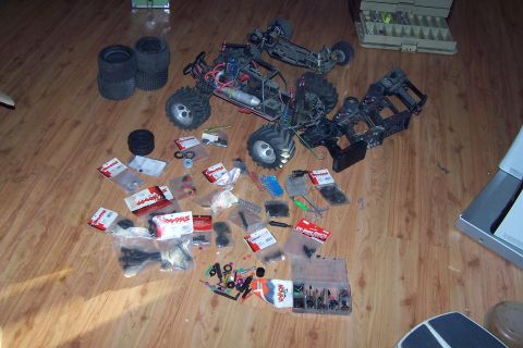 2004 Arctic Cat F-7 Firecat - Various remote control car parts and partially assembled vehicles are spread out on a wooden floor.