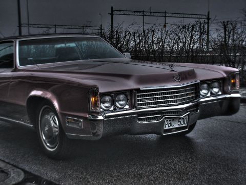 1998 Ford Crown Victoria - Maroon 1971 Cadillac Eldorado with distinctive grille and quad headlights, parked outdoors.