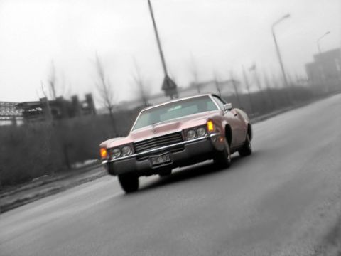 1998 Ford Crown Victoria - A classic Cadillac drives down a road on a cloudy day.