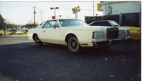 1998 Ford Crown Victoria - A cream-colored 1977 Lincoln Continental Mark V is parked next to a yellow car.