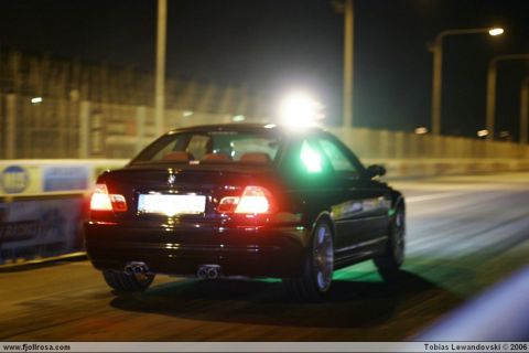 1998 Ford Crown Victoria - Rear view of a black BMW M3 E46 driving at night on a track.