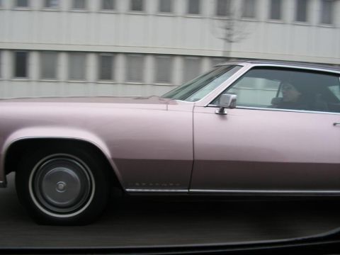 1998 Ford Crown Victoria - A pink Cadillac Eldorado is seen from the side, driving down a street.