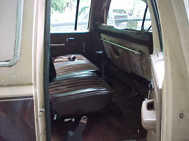 Rear interior of crew cab truck with brown bench seat seen through open door