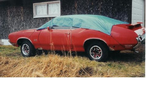 1978 Ford Bronco - Side view of a red convertible car, possibly a 1970 Oldsmobile 442, covered with a tarp.