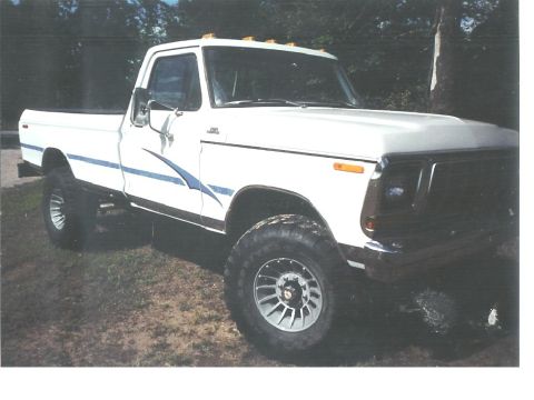 1978 Ford Bronco - This lifted pickup truck features a distinctive blue graphic along its side and custom wheels.