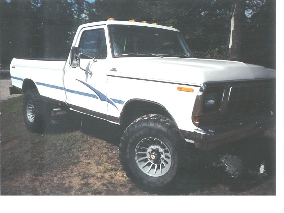White pickup truck with blue stripe on side, lifted suspension, and aftermarket wheels