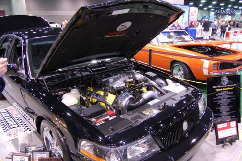 2003 Mercury Marauder - A black 2003 Mercury Marauder is displayed with its hood open, revealing a modified engine with yellow accents and a turbocharger.