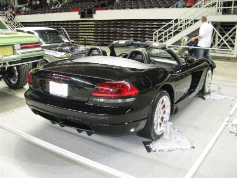 2003 Mercury Marauder - A black convertible sports car is displayed at an auto show with other vehicles.
