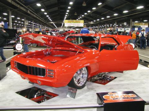 2003 Mercury Marauder - A bright red 1969 Camaro is displayed with its hood and doors open at an indoor car show.