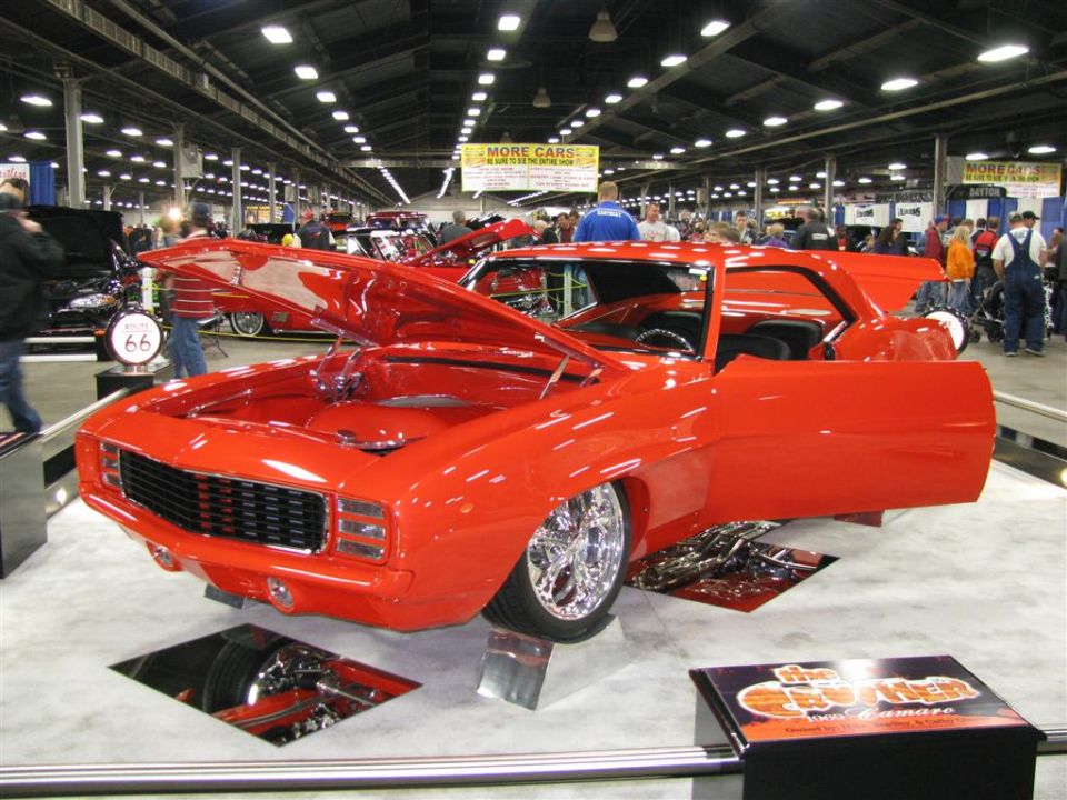 Red 1969 Camaro with hood and doors open, on display at a car show