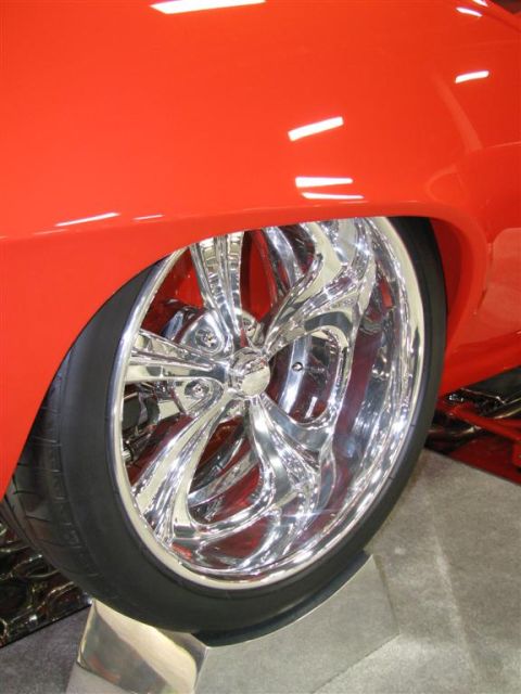2003 Mercury Marauder - A close-up of a custom chrome wheel on a red vehicle at a car show.
