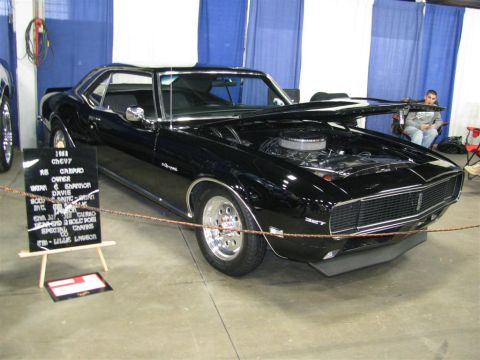 2003 Mercury Marauder - A black 1968 Chevrolet Camaro RS is displayed with its hood open at a car show.