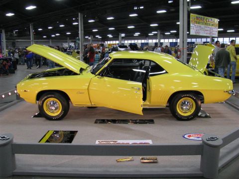 2003 Mercury Marauder - A bright yellow 1969 Chevrolet Camaro coupe is displayed with its hood and driver's door open at a car show.