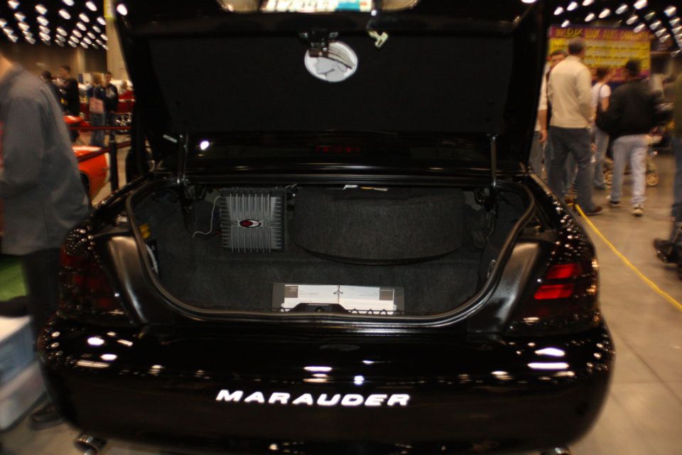 Black sedan's trunk open, showing audio amplifiers and the 'Marauder' badge on the rear