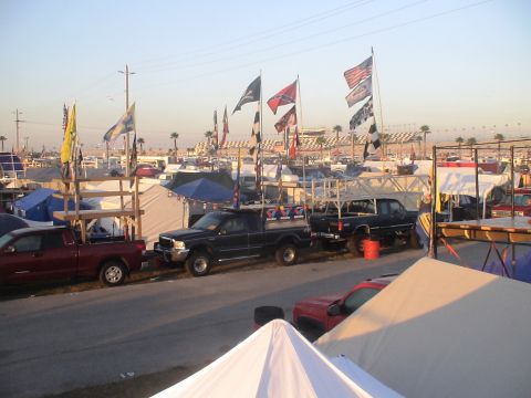 1993 Ford C-350 (Centurion Conversions) - A busy scene at a race track parking area with many tents and flags flying.
