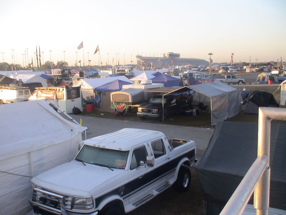 White Ford F-Series pickup truck with a dark stripe, parked at a campsite