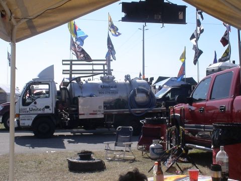 1993 Ford C-350 (Centurion Conversions) - A white tank truck with 'United' branding is parked next to a red pickup truck under a tent.
