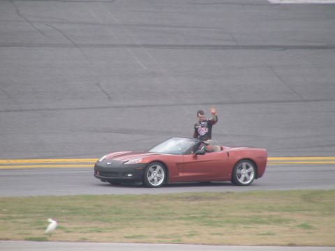 1993 Ford C-350 (Centurion Conversions) - Driver and passenger in a red convertible on a racetrack, possibly during an event.