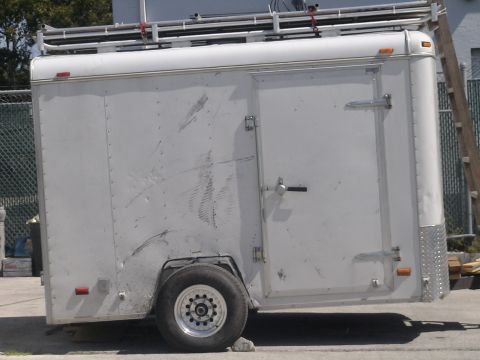 1993 Ford C-350 (Centurion Conversions) - Side view of a white cargo trailer with a roof rack and visible damage.