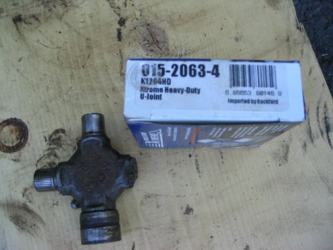 1986 Ford Bronco - A U-joint part and its packaging are shown on a wooden surface.