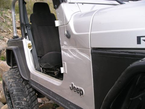 1986 Toyota Hilux - Close-up of a silver Jeep's open door and interior seat, with the Jeep logo on the door panel.