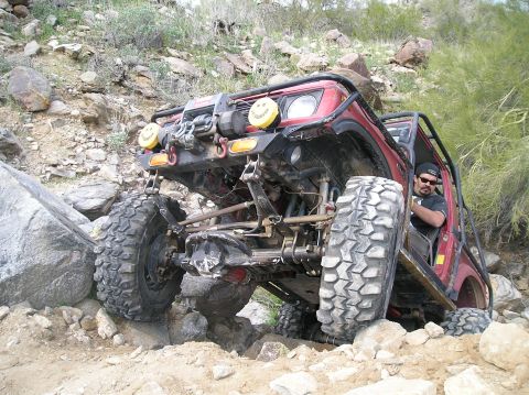 1986 Toyota Hilux - This heavily modified off-road vehicle tackles a challenging rocky trail with impressive articulation.